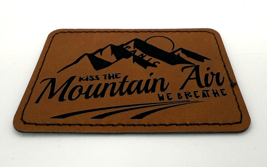 Kiss The Mountain Air Patch 3.5” x 2.5” | Laser Engraved | Rawhide/Black | Iron or stitch | Panic Fan Art
